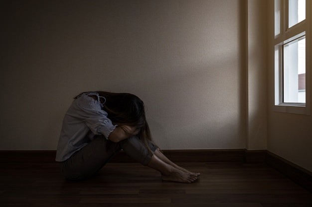 Depressed and stressed woman sitting on the floor alone