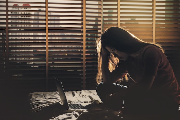 Depressed Women sitting head in hands when working with technology laptop