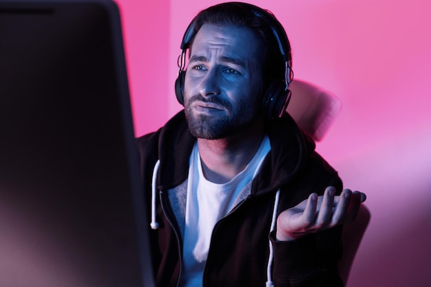 Depressed young man looking at the computer monitor and gesturing