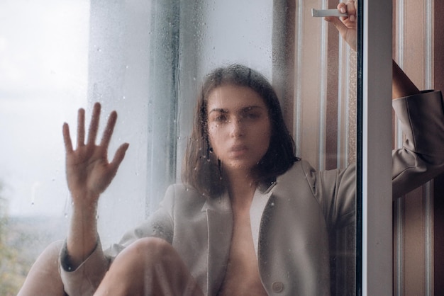 Depressed young woman near window at home closeup Sadness and disappointment