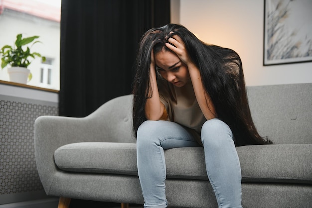 Depressed young woman on sofa at home