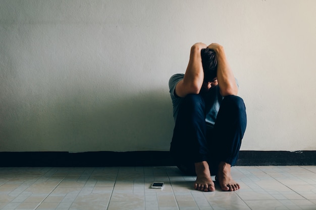 Depression concept.Man with depression sitting alone on the floor in the dark room