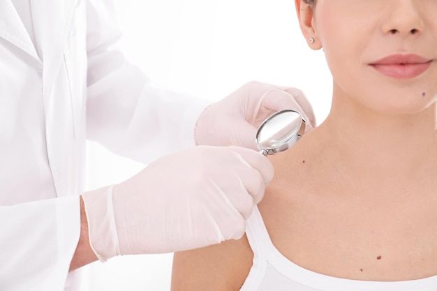 Photo dermatologist examining patient with magnifying glass in clinic closeup view