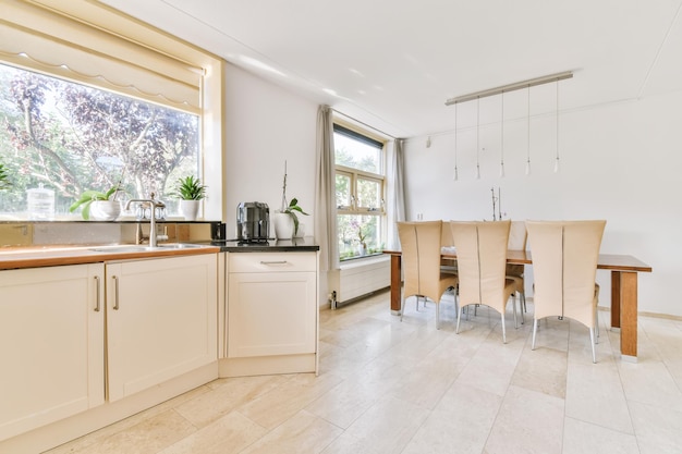 Design of a bright kitchen with big windows and dining room in the background