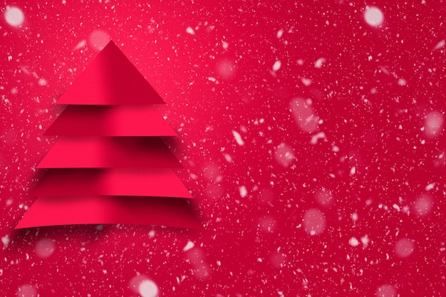 Design of red christmas tree with paper texture and snowy background. Christmas concept.