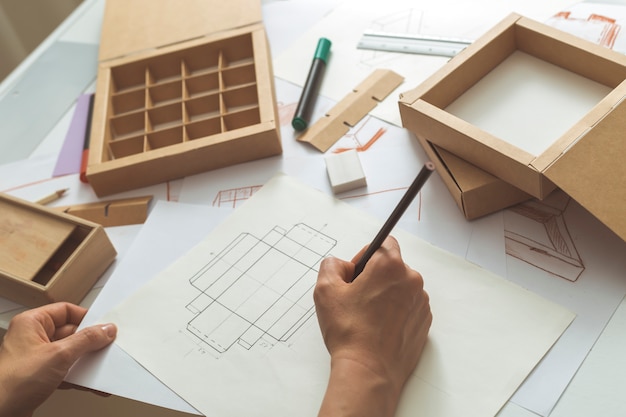 The designer draws sketches for cardboard packaging. 