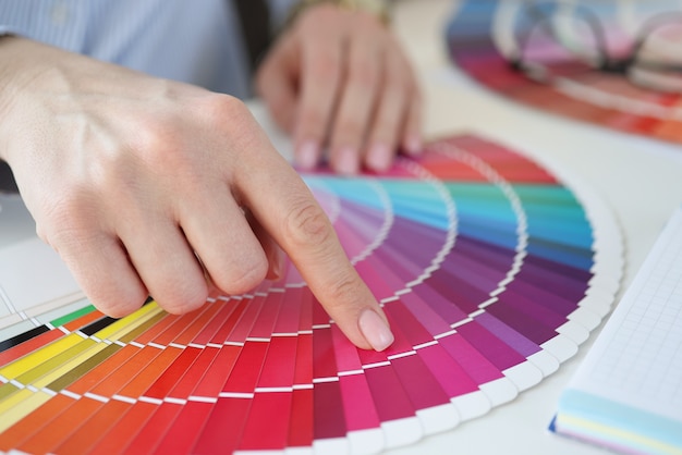 Designer holding color swatch at desk in office closeup. Interior design concept