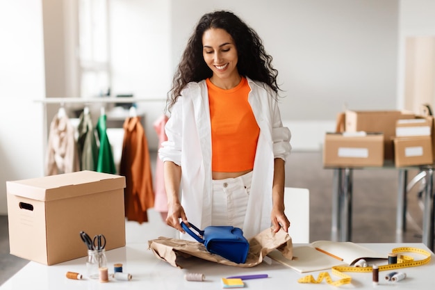 Designer wraps handbag in boutique preparing parcel in clothing store