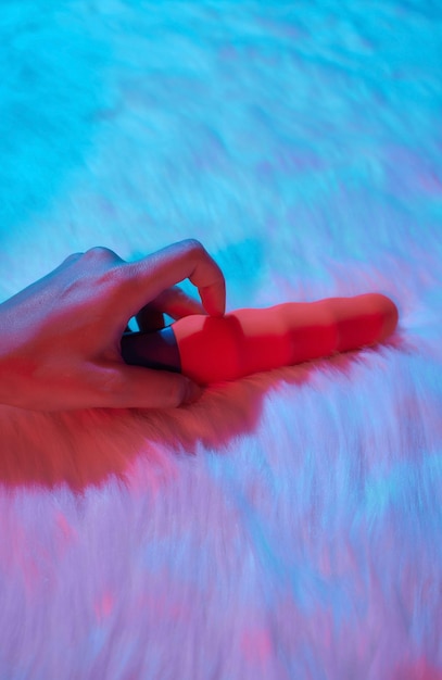 Desire concept Woman lying in bed holding a dildo vibrator in her hand to help herself