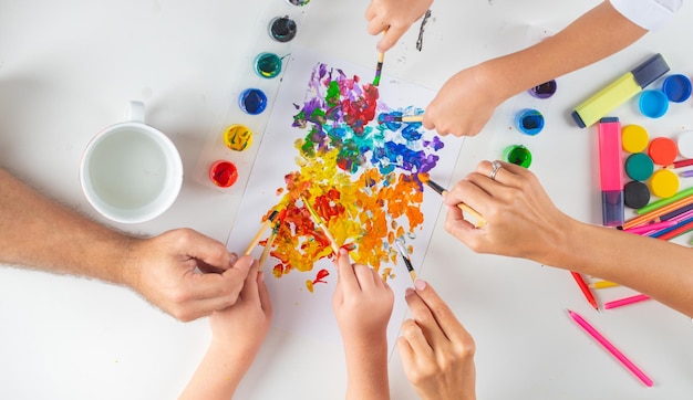 Desk of an artist hands with drawing painting colorful paints and pencil crayons on white background...