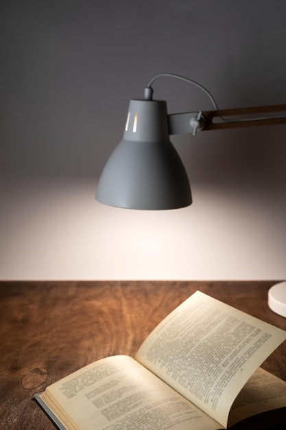 Desk lamp illuminates the workplace on the office desk and the opened book