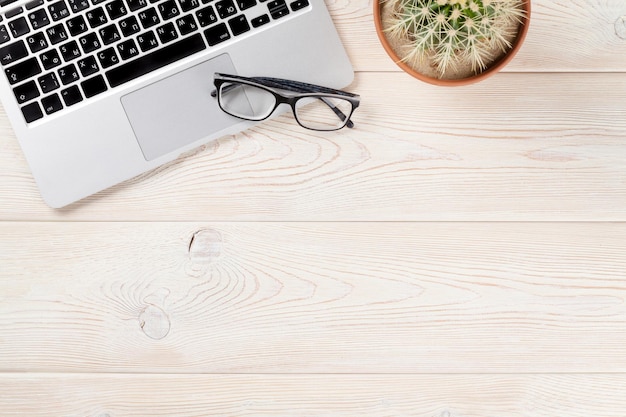 Desk with laptop cactus and glasses