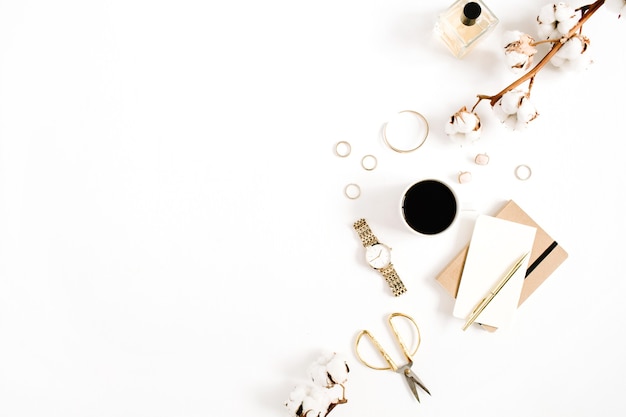 Desk with woman accessory collection golden watches, scissors, coffee cup, notebook and cotton branch on white background. Flat lay