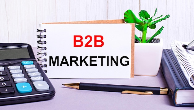 On the desktop are a calculator diaries a potted plant a pen and a notebook with the text B2B MARKETING