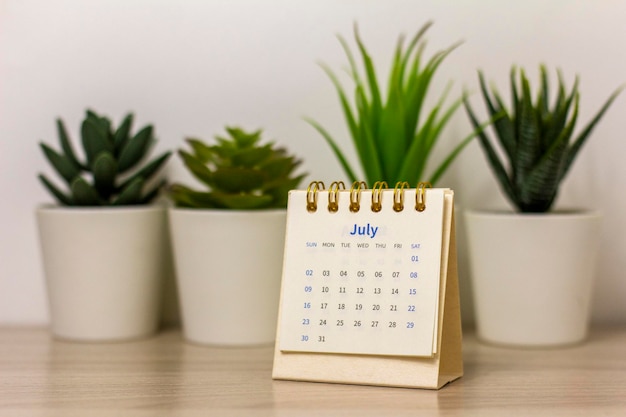 Desktop calendar for July 2023 on the table with a space to copy