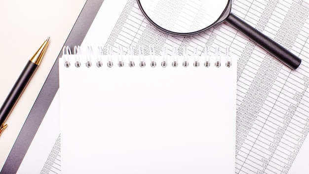 On the desktop, a magnifying glass, reports, a pen and a notebook with a place to insert text. Template. Business concept