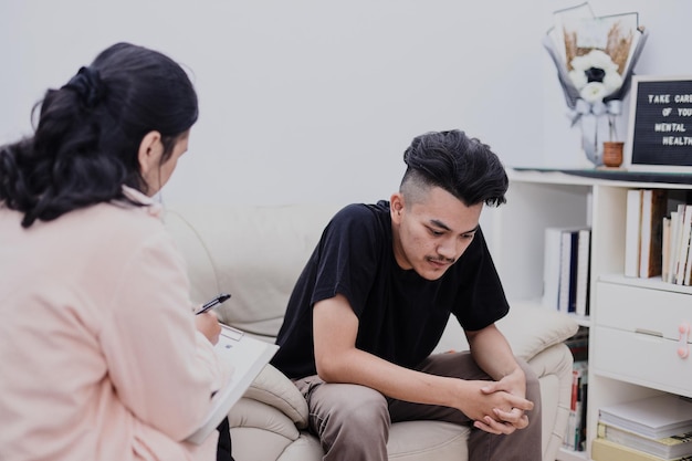 Despaired young male suffers from mental problems listens to female psychologist in clinic Psychol