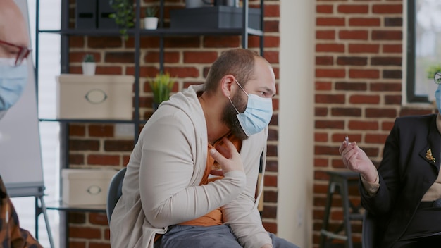 Desperate man complaining about anger management issues with therapist at aa meeting. Person with face mask explaining mental health problems and asking for guidance during pandemic.