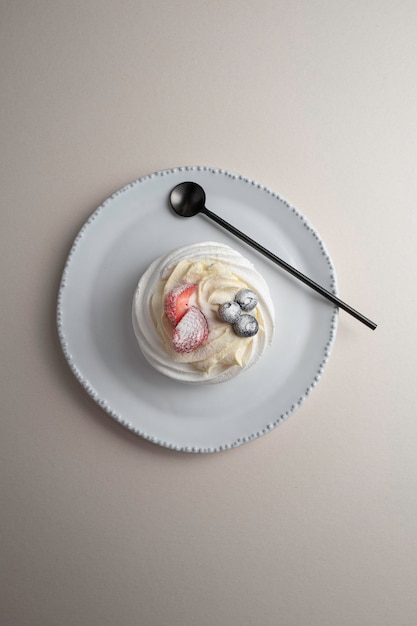 Dessert Anna Pavlova with strawberry and blueberry on a white plate with decor