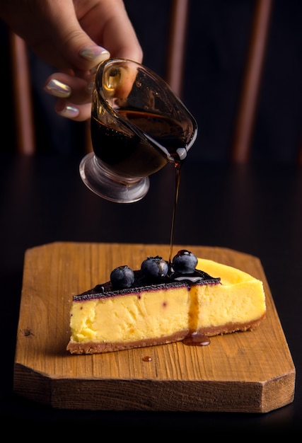 Dessert cheesecake with blueberries sprinkled with sauce on a dark background