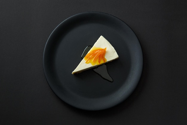 Dessert of cheesecake with jam on a black plate isolated on a black background