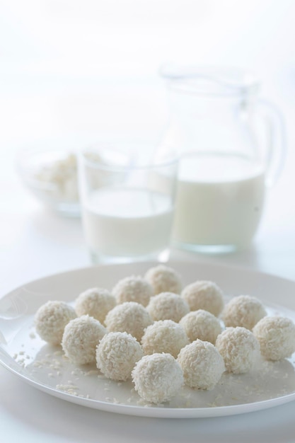 Dessert coconut cake and milk in a jug on a light background