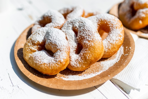 Dessert crumpet with powdered sugar on a cardboard plate.