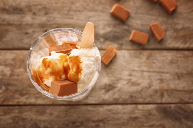 Dessert glass with vanilla ice cream caramel sauce and candy on table