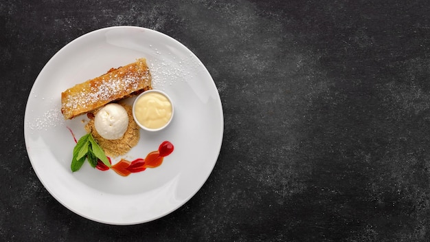 Dessert strudel with apples and ice cream on a dark background