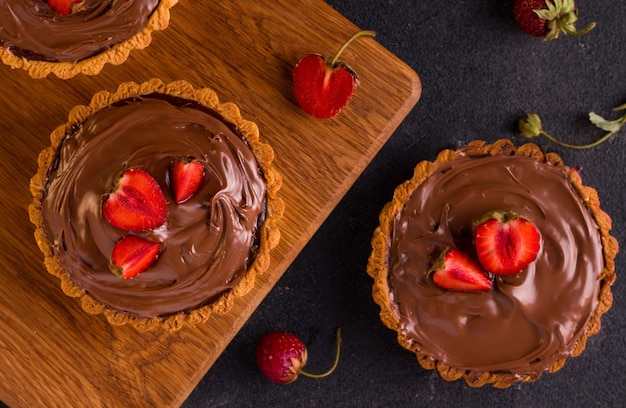 Dessert tart with nut butter and strawberries on a wooden board. View from above