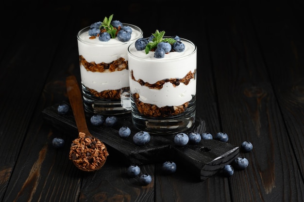 Dessert with cottage cheese fresh blueberries and granola in a glass on rustic background