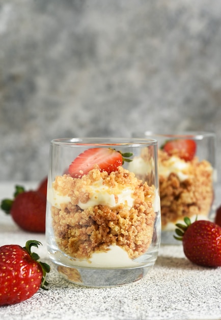 Dessert with crumbs, cream and strawberries. Cheesecake in a glass.