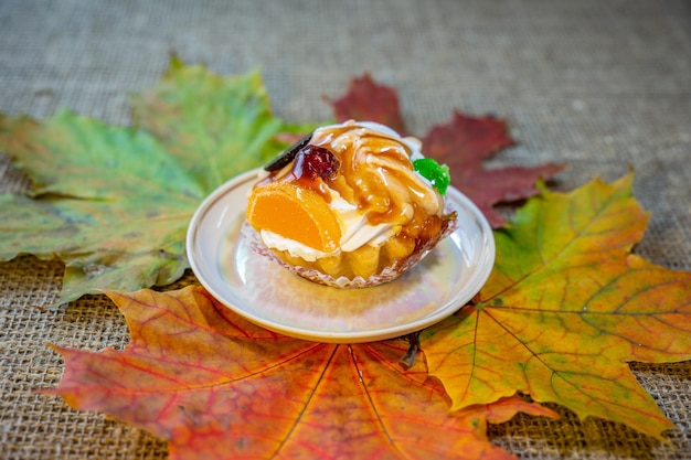 Photo dessert with orange and marmalade on the background of autumn leaves dessert tartlet with cream and