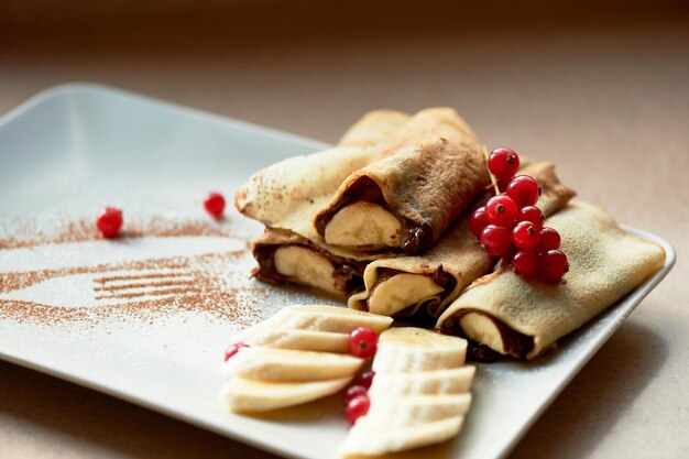 Desserthot pancakes with chocolate spread and banana Decorated with currantsSweet dessert