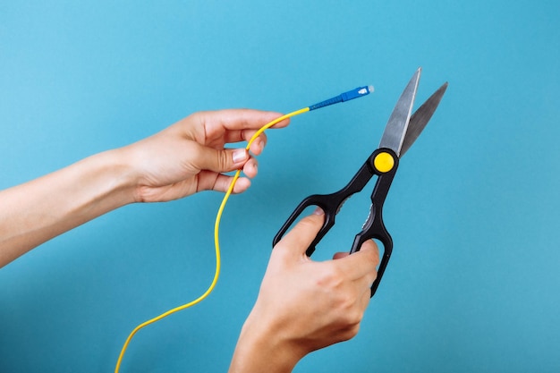 Destroy optical fiber with scissors. Isolated on blue.