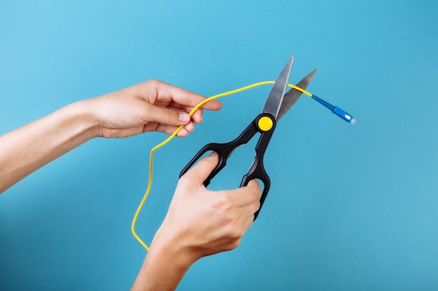 Destroy optical fiber with scissors. Isolated on blue.