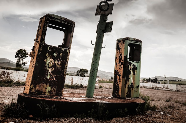 The destroyed rusty gas station against the background of the gloomy textured sky leave the scary pl