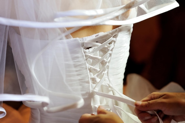 Detail of bridesmaid fixing bride39s wedding dress