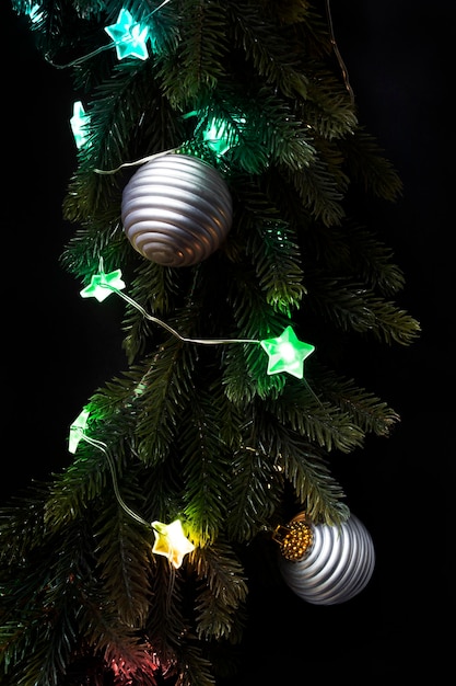 Detail of christmas wreath with colorful led lights and balls closeup on dark background