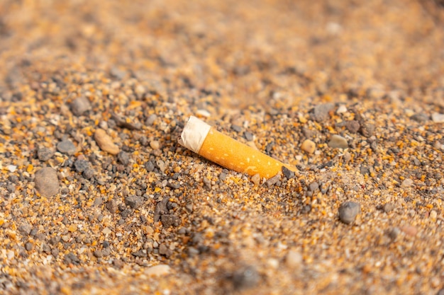 Detail of a cigarette thrown in the sand on the beach garbage little respect for nature