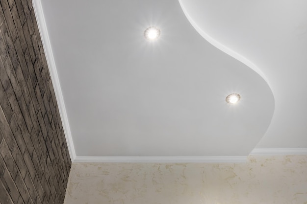 Detail of corner ceiling with intricate crown molding Suspended ceiling and drywall construction in empty room in apartment or house Stretch ceiling white and complex shape