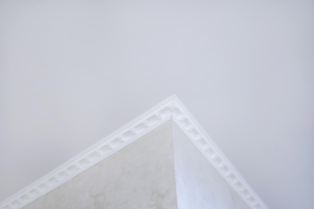 Detail of corner ceiling with intricate crown molding Suspended ceiling and drywall construction in empty room in apartment or house Stretch ceiling white and complex shape