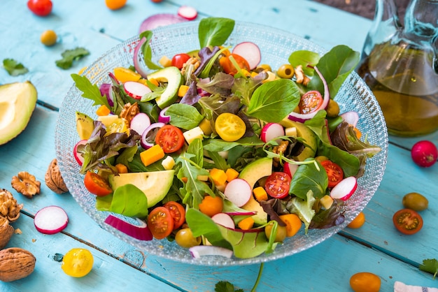 Detail of a fresh salad with arugula avocado cheese tomato radishes onion and walnuts