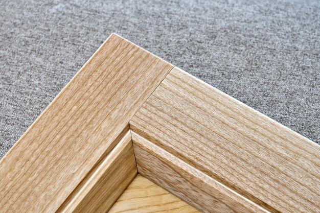 Detail of furniture facade made of light veneer and solid ash wood on gray textile background