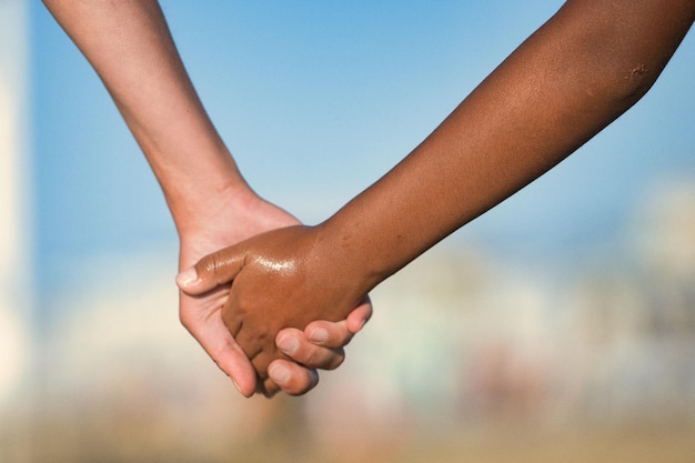 Detail of hands crossing of Caucasian woman and darkskinned child