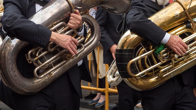 Detail of the hands of two musicians parading in the street playing the tuba