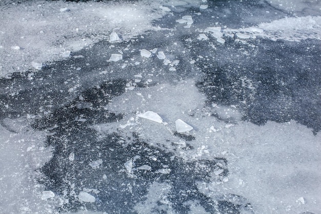 Detail on ice layer of completely frozen river, with snow and ice crystals on top.