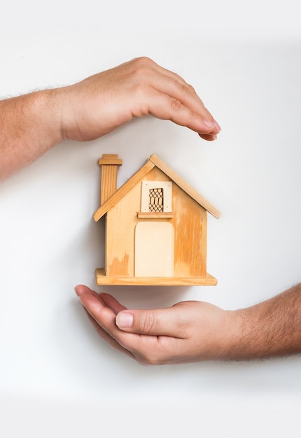 Detail of male hands surrounding a small wooden house