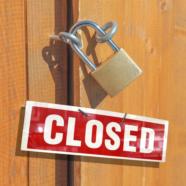 Detail of padlock on a wooden door with closed sign