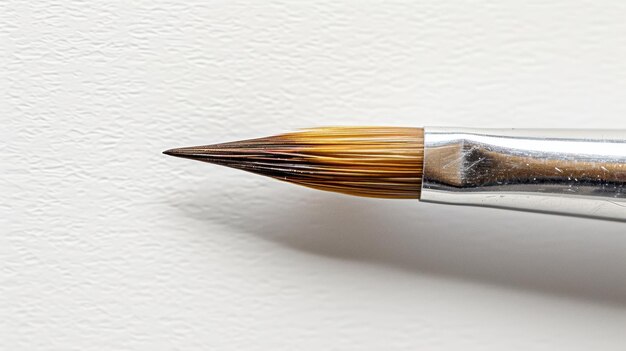 Photo detail of a paintbrush resting on a white canvas